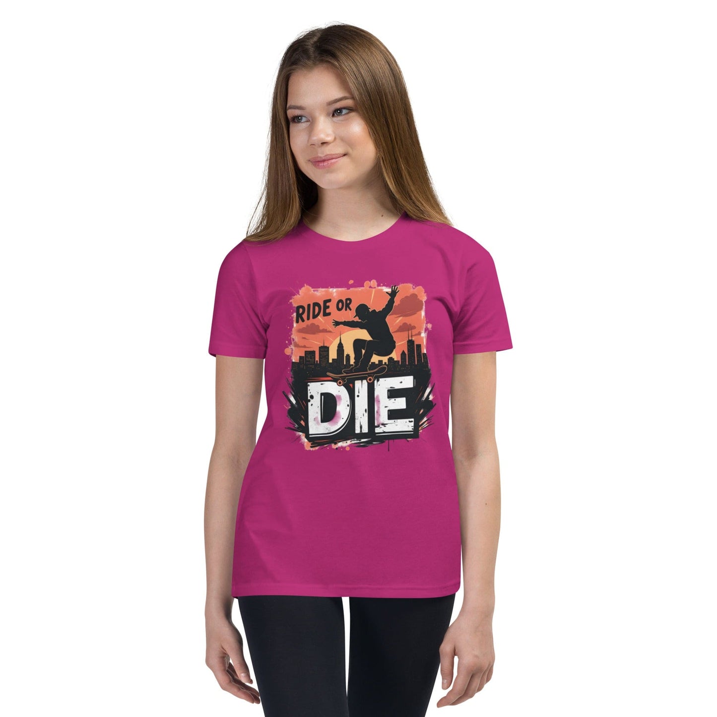 Teen girl wearing pink T-shirt with “Ride or Die” text, skater silhouette, sunset city background and bold urban print – ccanvas