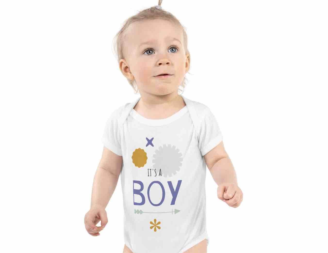 Smiling toddler in white “It’s a BOY” onesie from the Ccanvas Toddler Collection – gender reveal-ready, soft cotton comfort