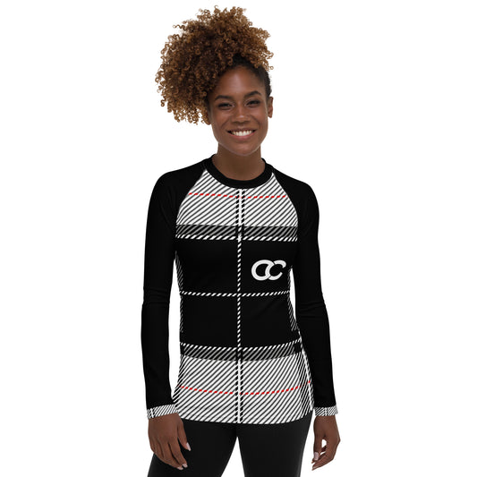 Woman wearing black and white plaid long sleeve top with red accents and logo on front