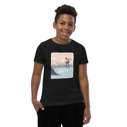 Boy wearing a black youth T-shirt with a skateboarding graphic and city skyline, reading “Live to Skate”