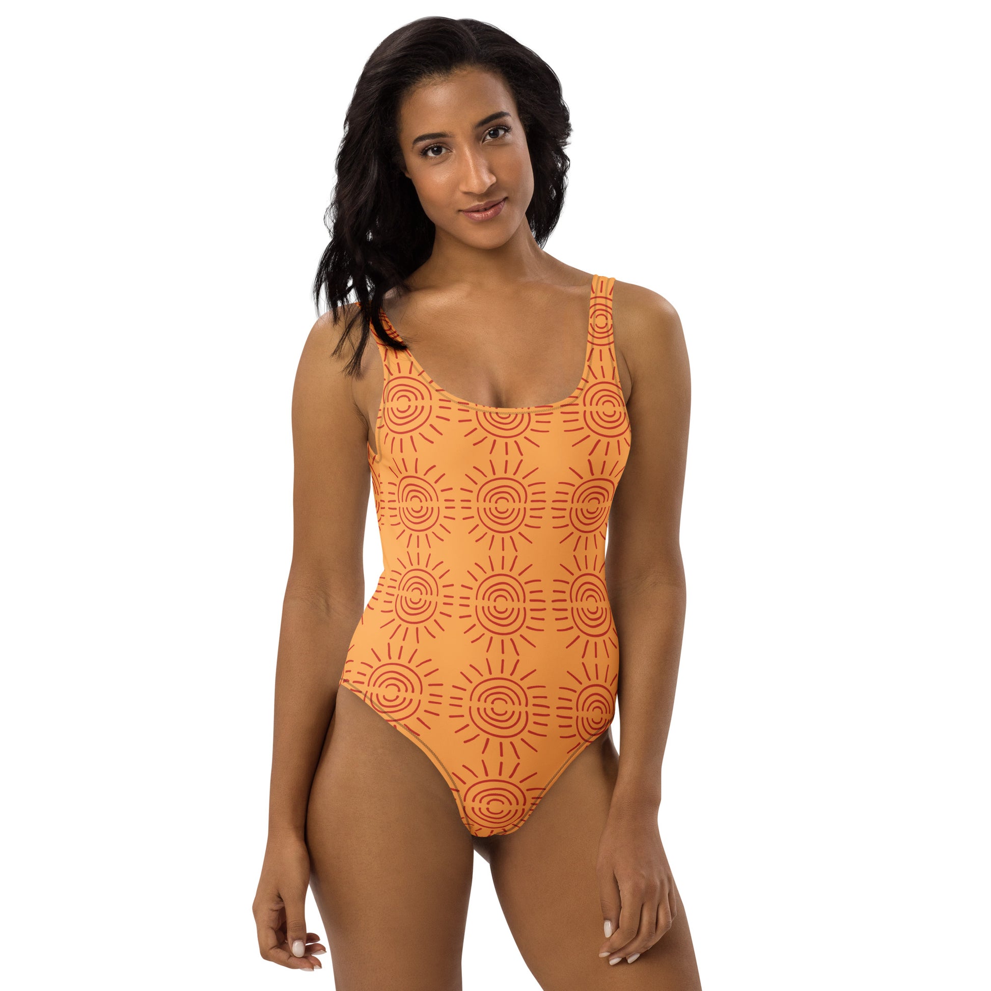 Model wearing an orange one-piece swimsuit with a radiant sunburst geometric print by CCANVAS.
