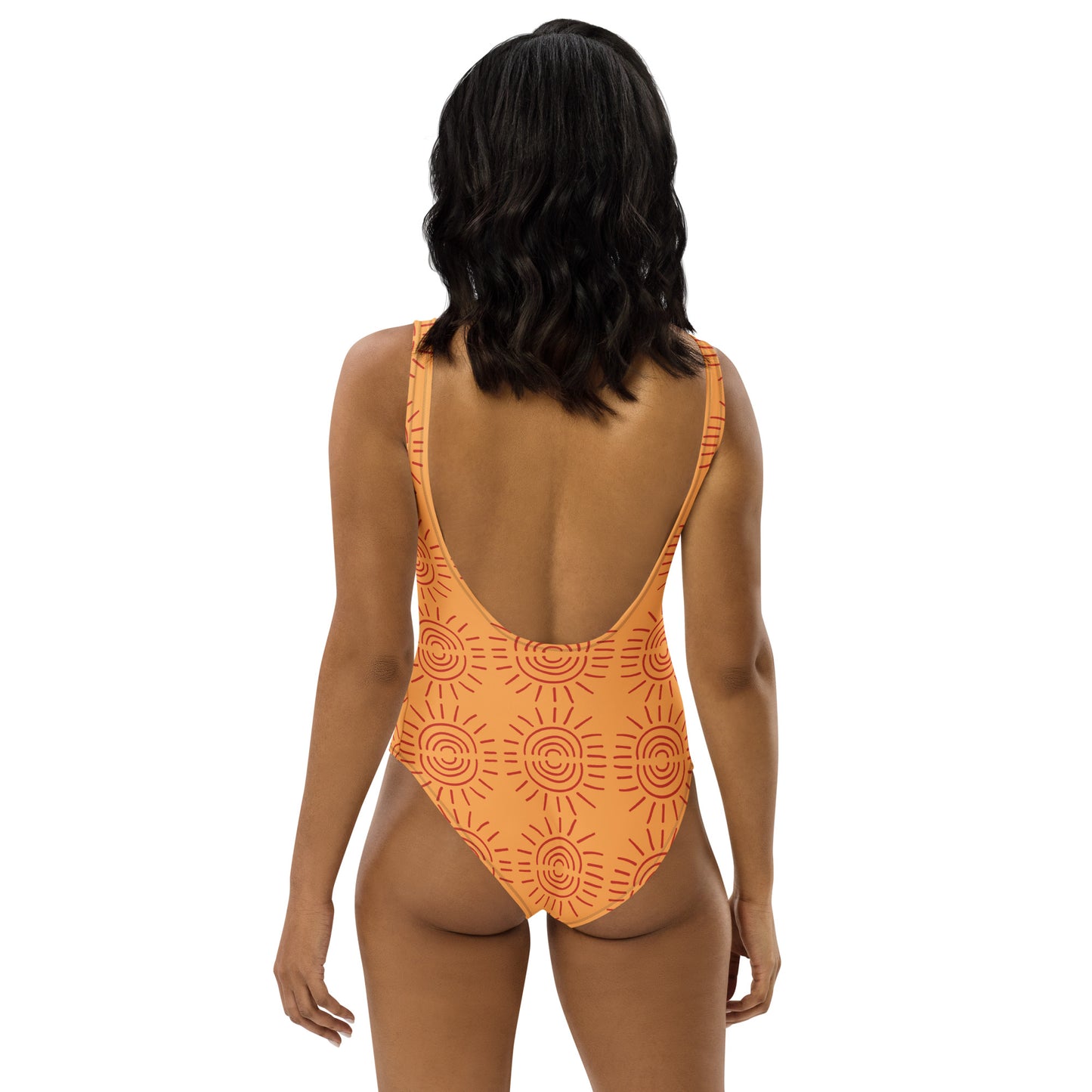 Back view of model wearing an orange sunburst swimsuit featuring a deep scoop back design by CCANVAS.

