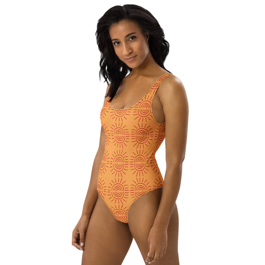 
Side view of model in an orange sunburst swimsuit showing the scoop neck and athletic fit by CCANVAS.
